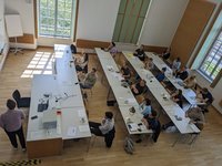 Several listeners follow a speaker's presentation in a seminar room.